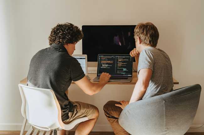 Two developers pair programming at a laptop