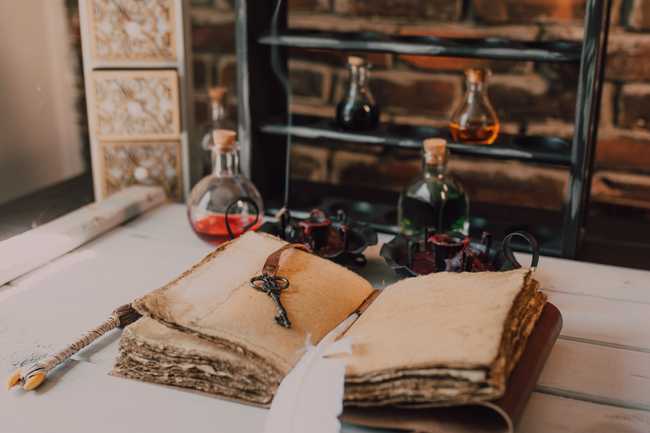 An Old Book and Candles on a Wooden Table with Glass Bottles